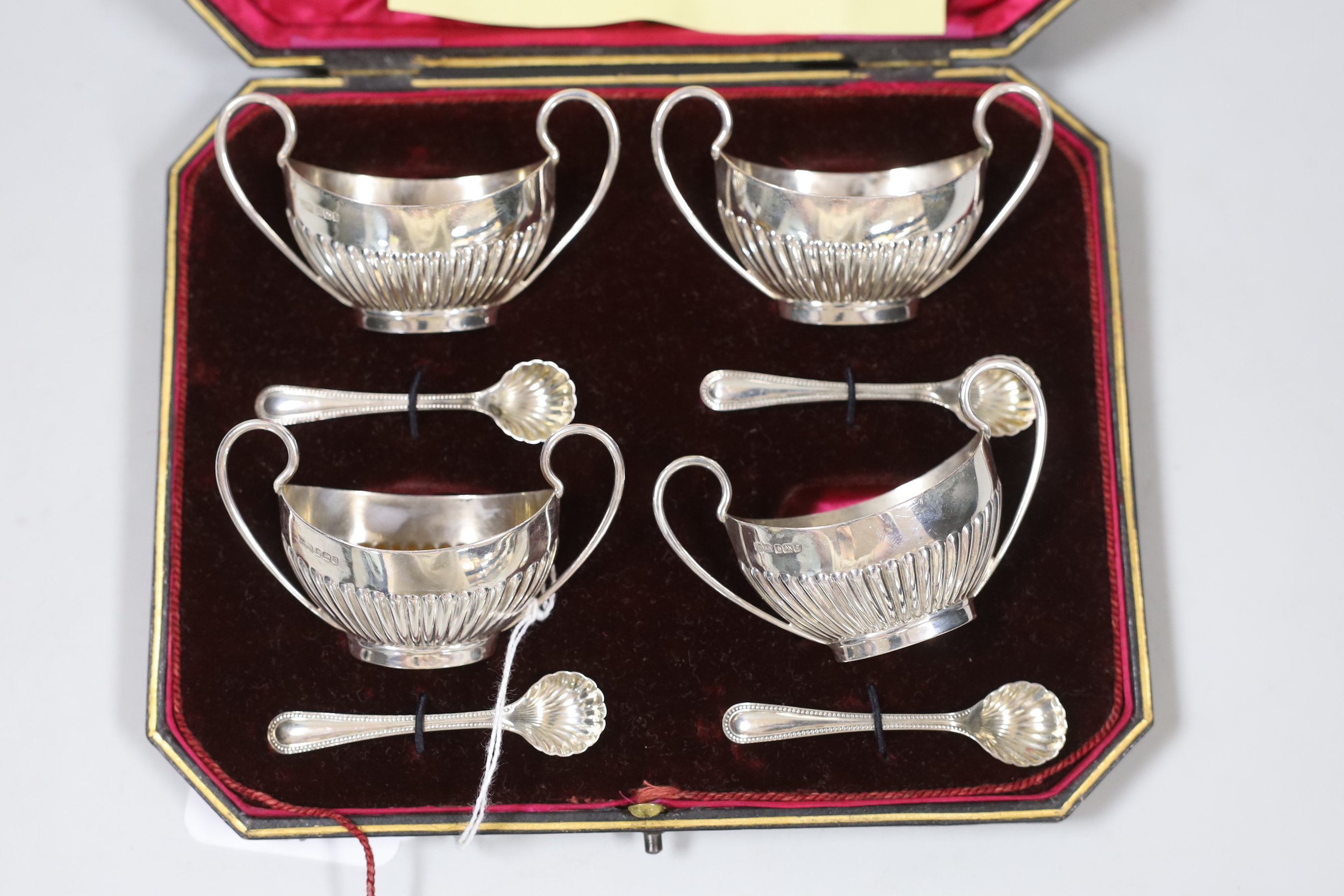 A cased set of four Edwardian demi-fluted silver two handled salts and four spoons, James Dixon & Sons, Sheffield, 1908.